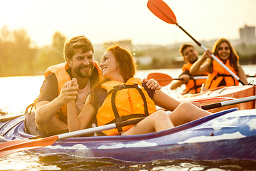 Image showing Happy friends kayaking on river with sunset on the background