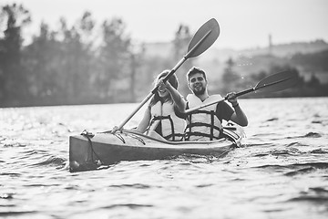 Image showing Happy couple kayaking on river with sunset on the background