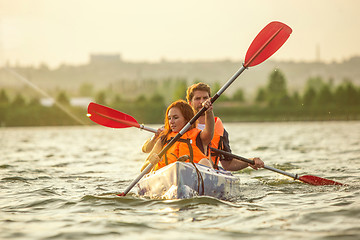 Image showing Happy couple kayaking on river with sunset on the background