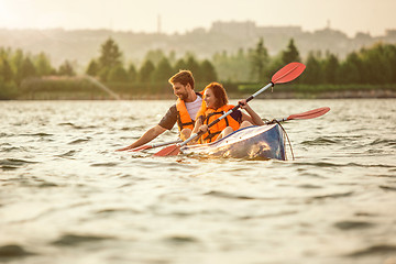 Image showing Happy couple kayaking on river with sunset on the background