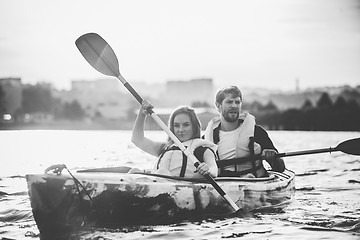 Image showing Happy couple kayaking on river with sunset on the background