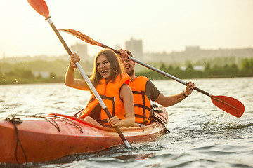 Image showing Happy couple kayaking on river with sunset on the background