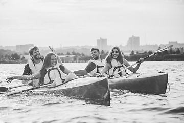 Image showing Happy friends kayaking on river with sunset on the background