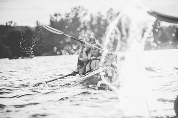 Image showing Happy couple kayaking on river with sunset on the background