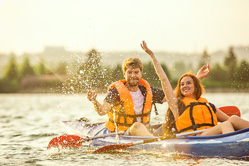 Image showing Happy couple kayaking on river with sunset on the background