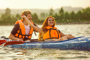 Image showing Happy couple kayaking on river with sunset on the background