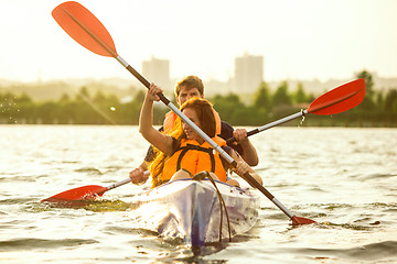 Image showing Happy couple kayaking on river with sunset on the background