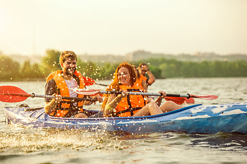 Image showing Happy friends kayaking on river with sunset on the background