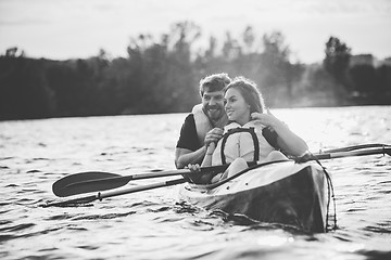 Image showing Happy couple kayaking on river with sunset on the background