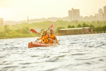 Image showing Happy couple kayaking on river with sunset on the background