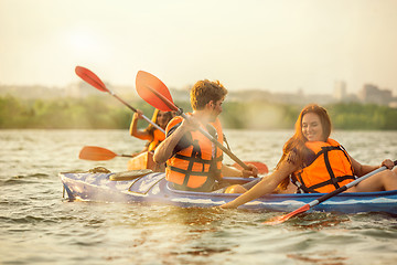 Image showing Happy friends kayaking on river with sunset on the background