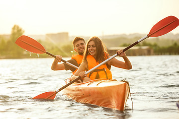 Image showing Happy couple kayaking on river with sunset on the background