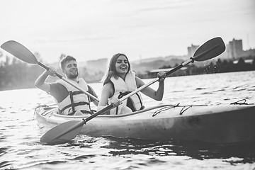 Image showing Happy couple kayaking on river with sunset on the background