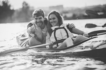 Image showing Happy couple kayaking on river with sunset on the background