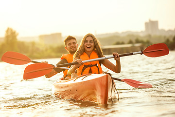 Image showing Happy couple kayaking on river with sunset on the background