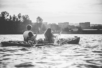 Image showing Happy couple kayaking on river with sunset on the background