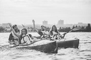 Image showing Happy friends kayaking on river with sunset on the background