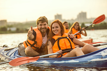 Image showing Happy friends kayaking on river with sunset on the background