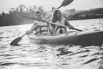 Image showing Happy couple kayaking on river with sunset on the background