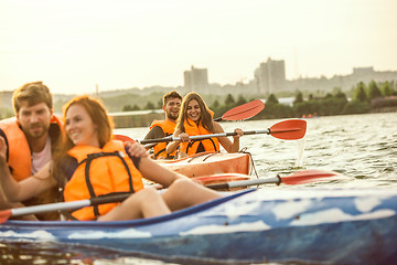 Image showing Happy friends kayaking on river with sunset on the background