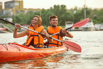 Image showing Happy couple kayaking on river with sunset on the background