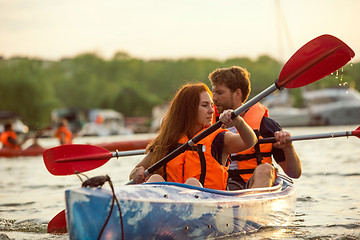 Image showing Happy couple kayaking on river with sunset on the background