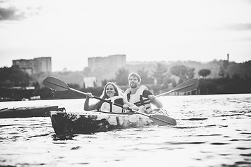 Image showing Happy couple kayaking on river with sunset on the background