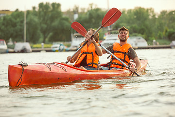 Image showing Happy couple kayaking on river with sunset on the background