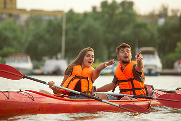 Image showing Happy couple kayaking on river with sunset on the background