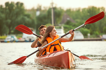 Image showing Happy couple kayaking on river with sunset on the background