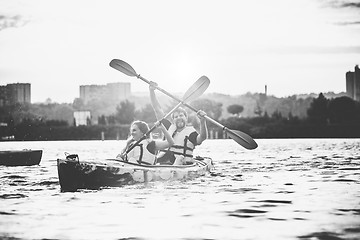 Image showing Happy couple kayaking on river with sunset on the background