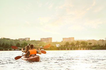 Image showing Happy couple kayaking on river with sunset on the background