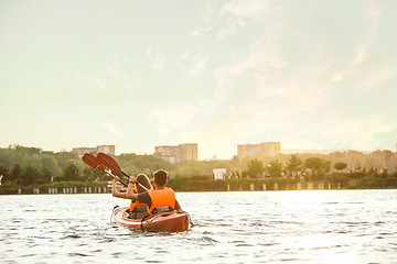 Image showing Happy couple kayaking on river with sunset on the background