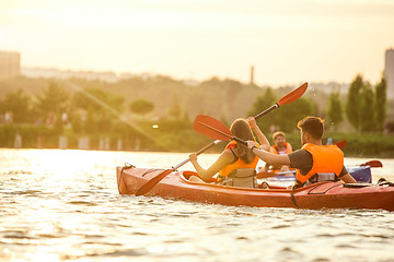 Image showing Happy couple kayaking on river with sunset on the background