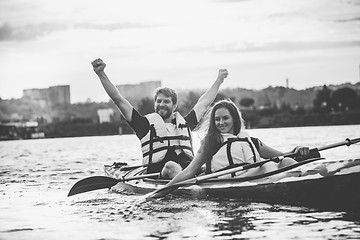 Image showing Happy couple kayaking on river with sunset on the background