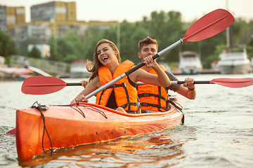 Image showing Happy couple kayaking on river with sunset on the background