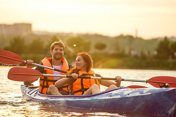 Image showing Happy couple kayaking on river with sunset on the background