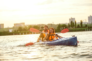 Image showing Happy couple kayaking on river with sunset on the background