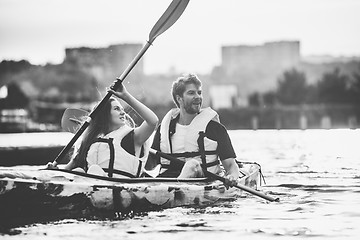 Image showing Happy couple kayaking on river with sunset on the background