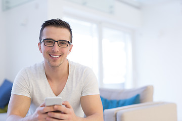 Image showing young man using a mobile phone  at home