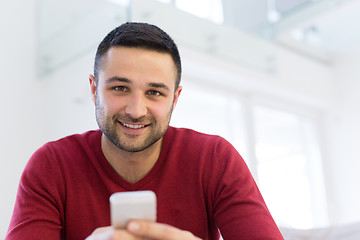 Image showing young man using a mobile phone  at home