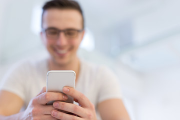 Image showing young man using a mobile phone  at home