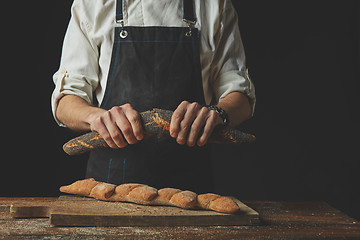 Image showing Men\'s hands hold divided baguette halves