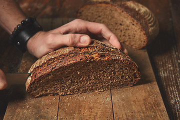 Image showing Hands cutting rye bread