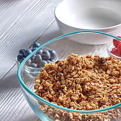 Image showing Organic homemade Granola Cereal with oats and fresh berries. Texture oatmeal granola or muesli in aglass bowl on a gray background.