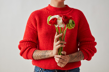 Image showing A beautiful bouquet of flowers of a Ranunculus holding a girl around a gray background.