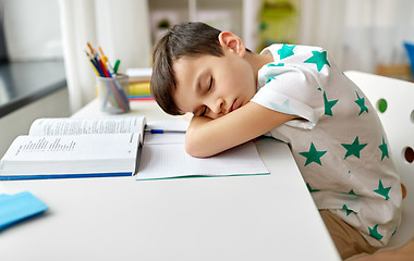 Image showing tired student boy sleeping on table at home