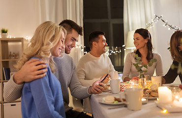 Image showing happy couple with smartphone at family tea party