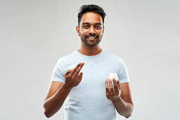 Image showing happy indian man applying cream to face