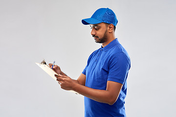 Image showing happy indian delivery man with clipboard in blue